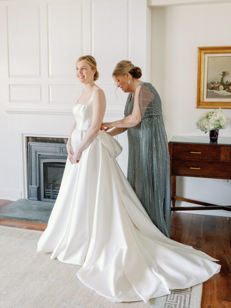 Bride's mom helping her put. on her wedding dress at the Woodstock Inn