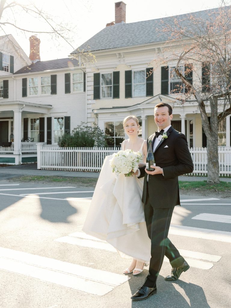 Bride and groom holding a bottle of champagne for spring wedding at the Woodstock Inn in Vermont