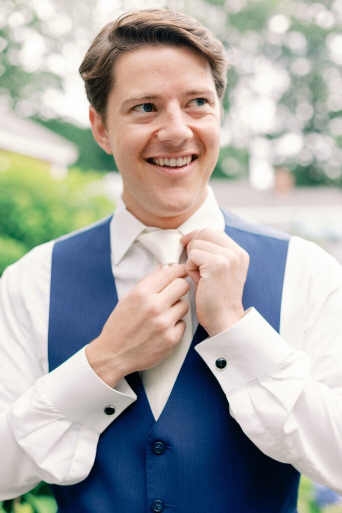 Groom putting on his tie for summer wedding