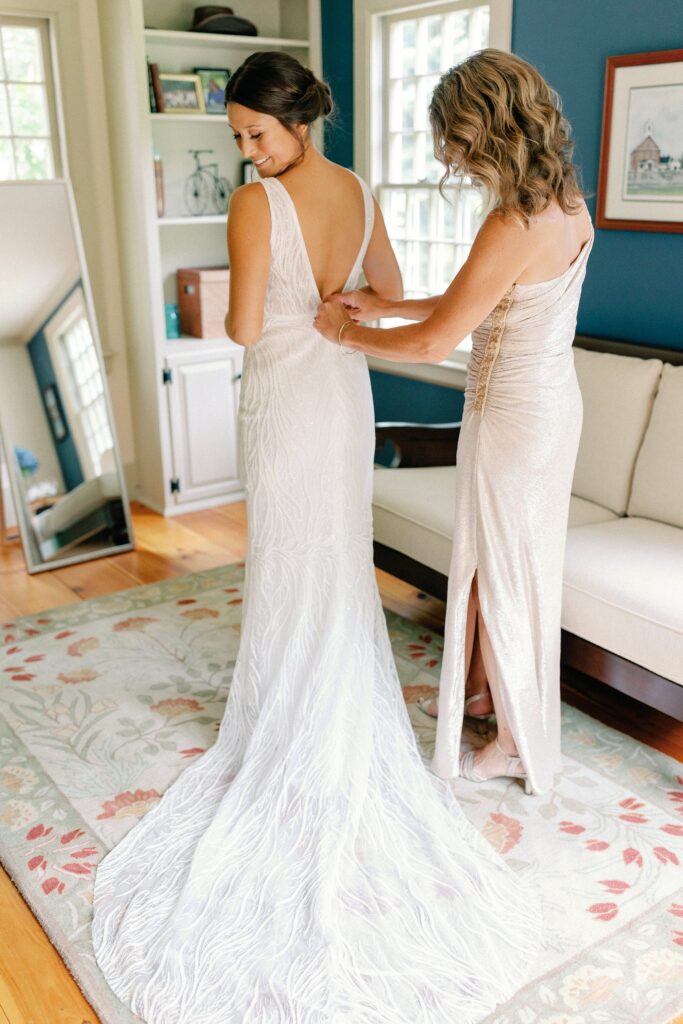 Bride putting in her wedding gown with the help of her mom for Wentworth by the Sea wedding