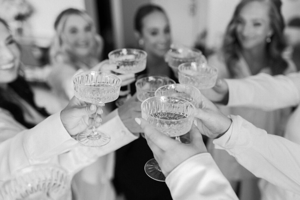 Black and white photos of bridesmaids cheersing with champagne while getting ready