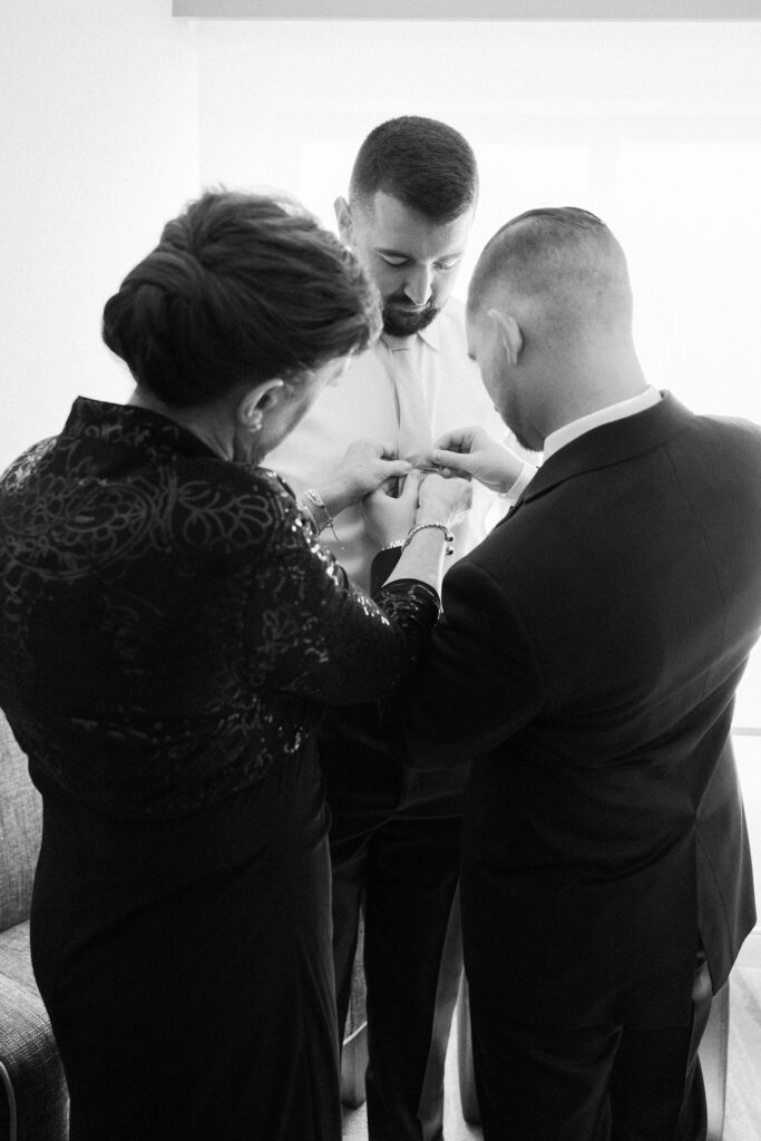 Groom getting help putting on his tie clip before wedding