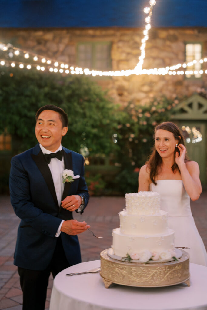 Bride and groom candid photo cutting wedding cake in courtyard at Willowdale Estate