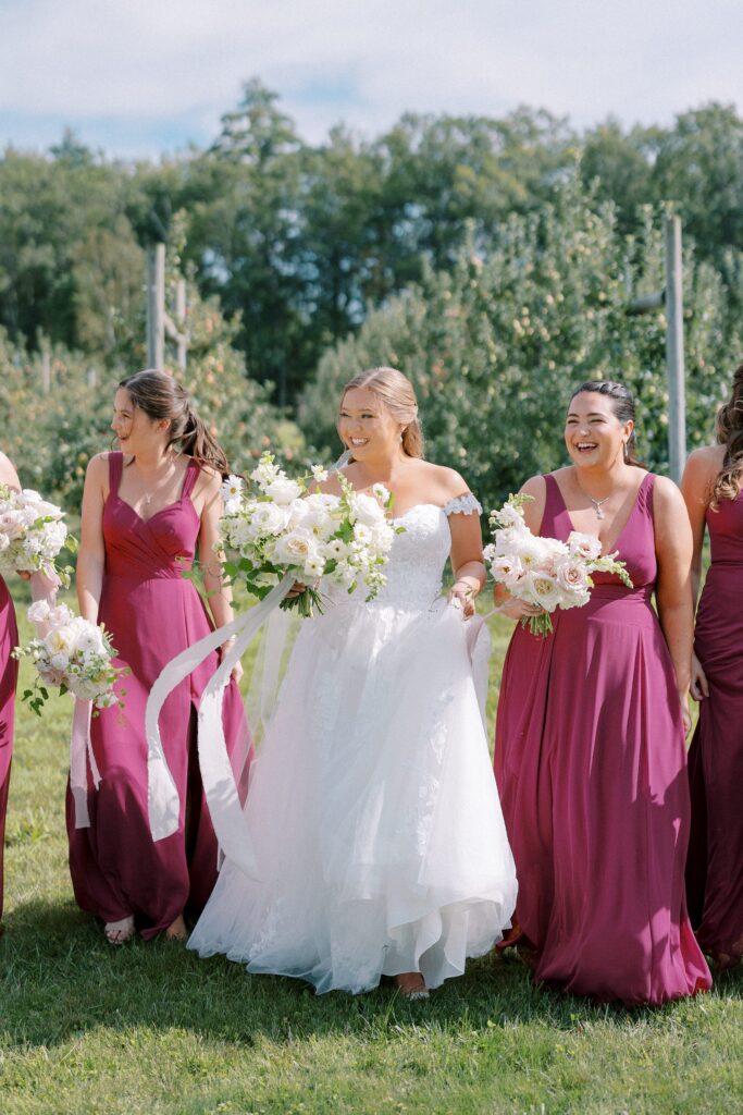 Bride and bridesmaids candid portrait in the orchard wearing mauve colored dresses