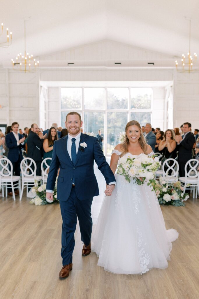 Indoor ceremony at The Greenery at McKenzie's Farm Wedding with bride and groom walking down the aisle