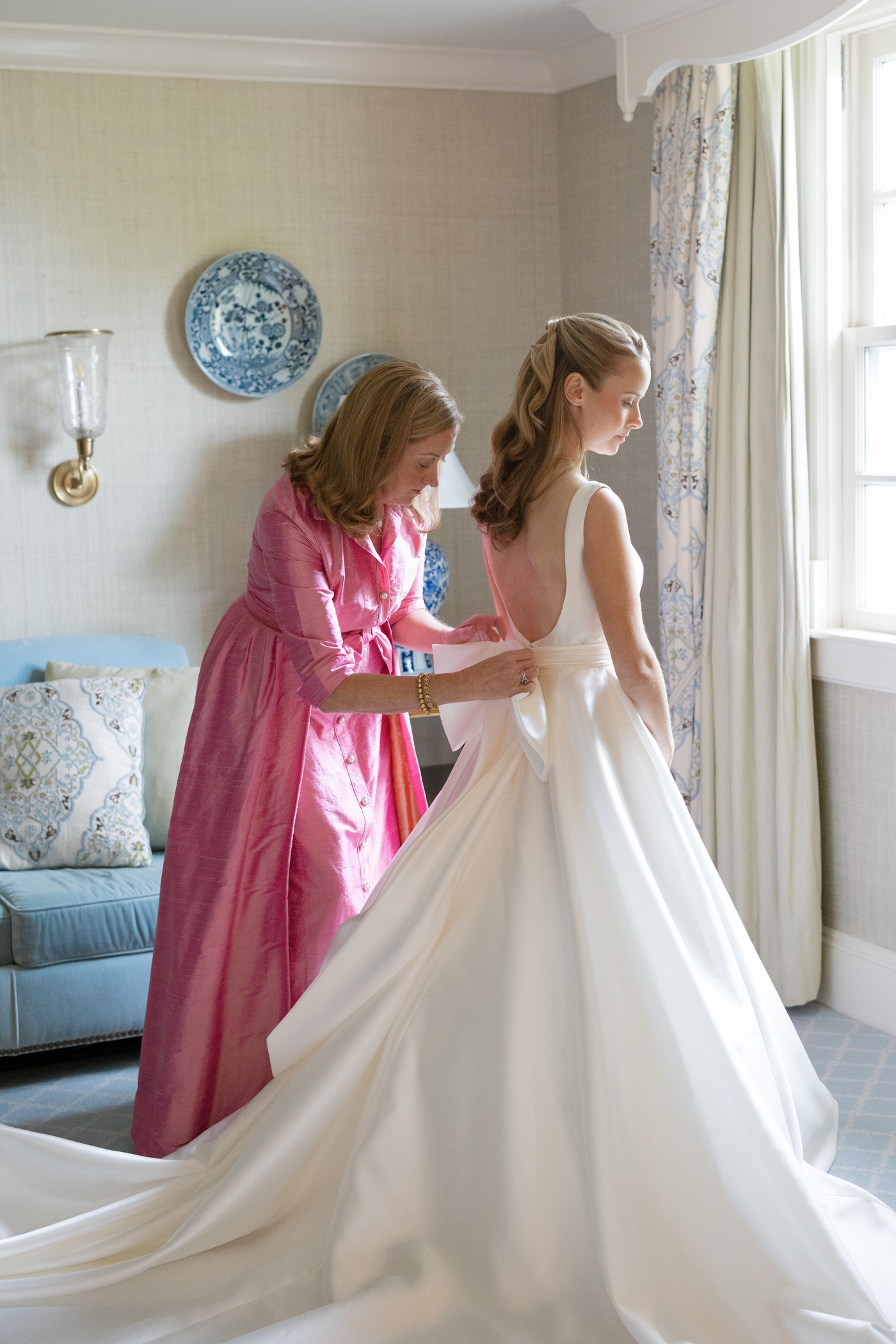 Mother of the bride helping bride with her wedding dress