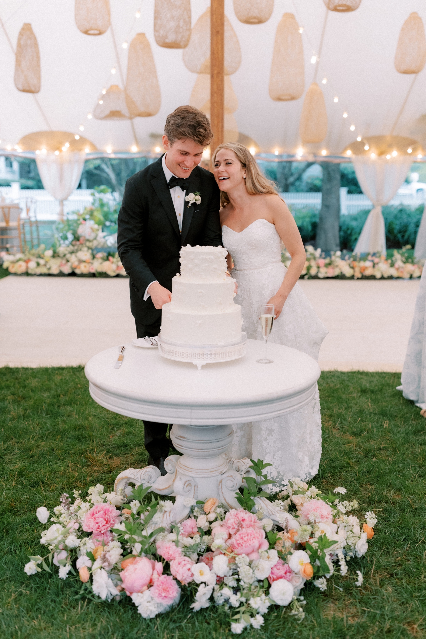 Wedding cake on a white pedestal with a pink, orange, and white floral meadow