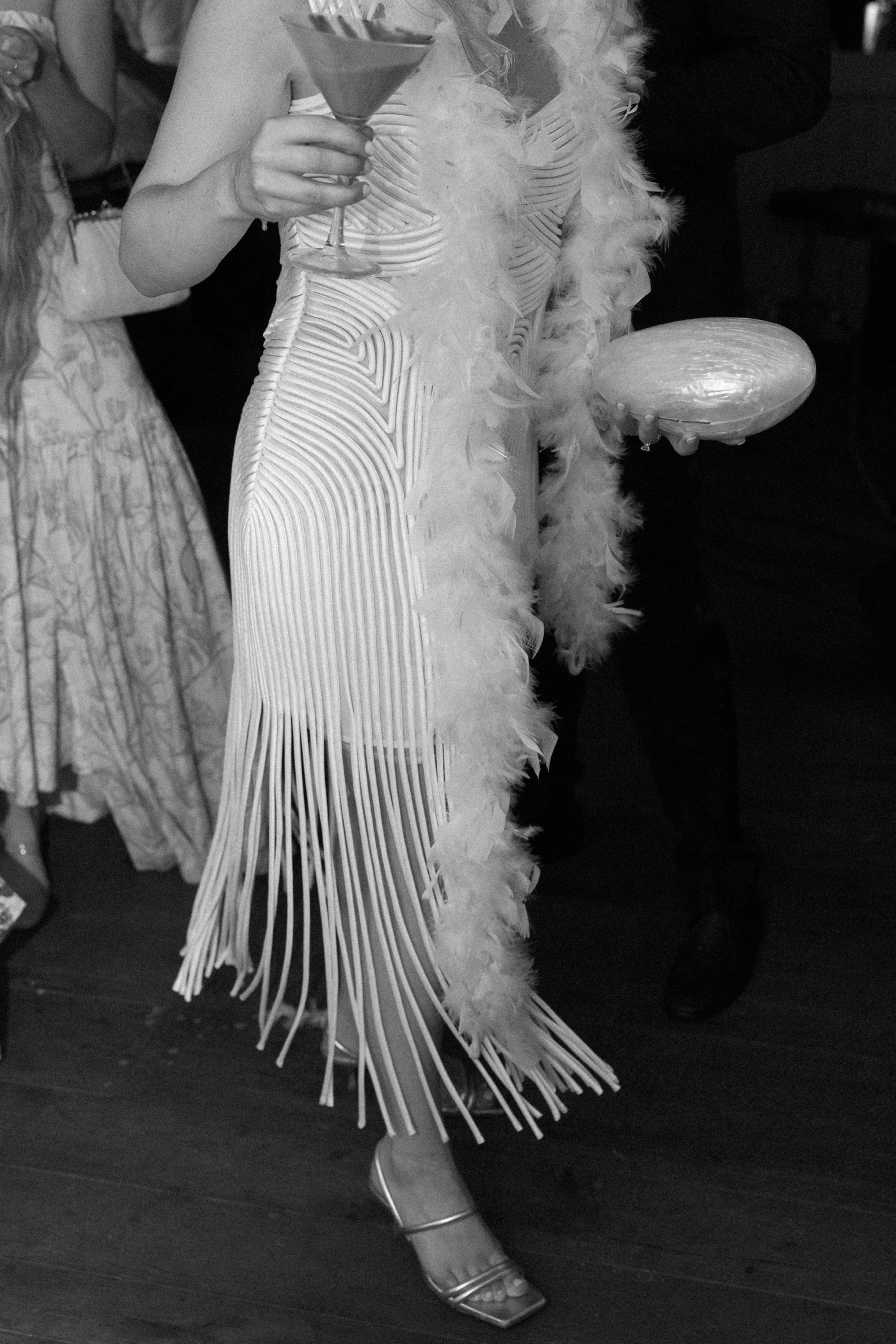 Bride wearing a fringed maxi dress and feather boa for her wedding reception