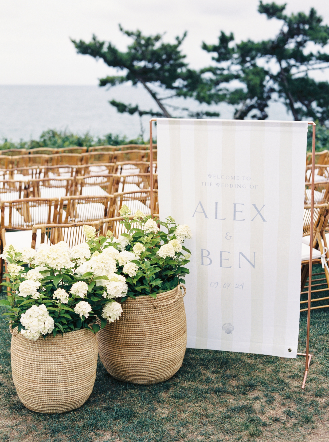 Wicker baskets with white hydrangeas and custom fabric sign at a Cape Cod wedding